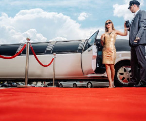 Private chauffeur in Dubai assisting VIP guest out of luxury limousine on red carpet